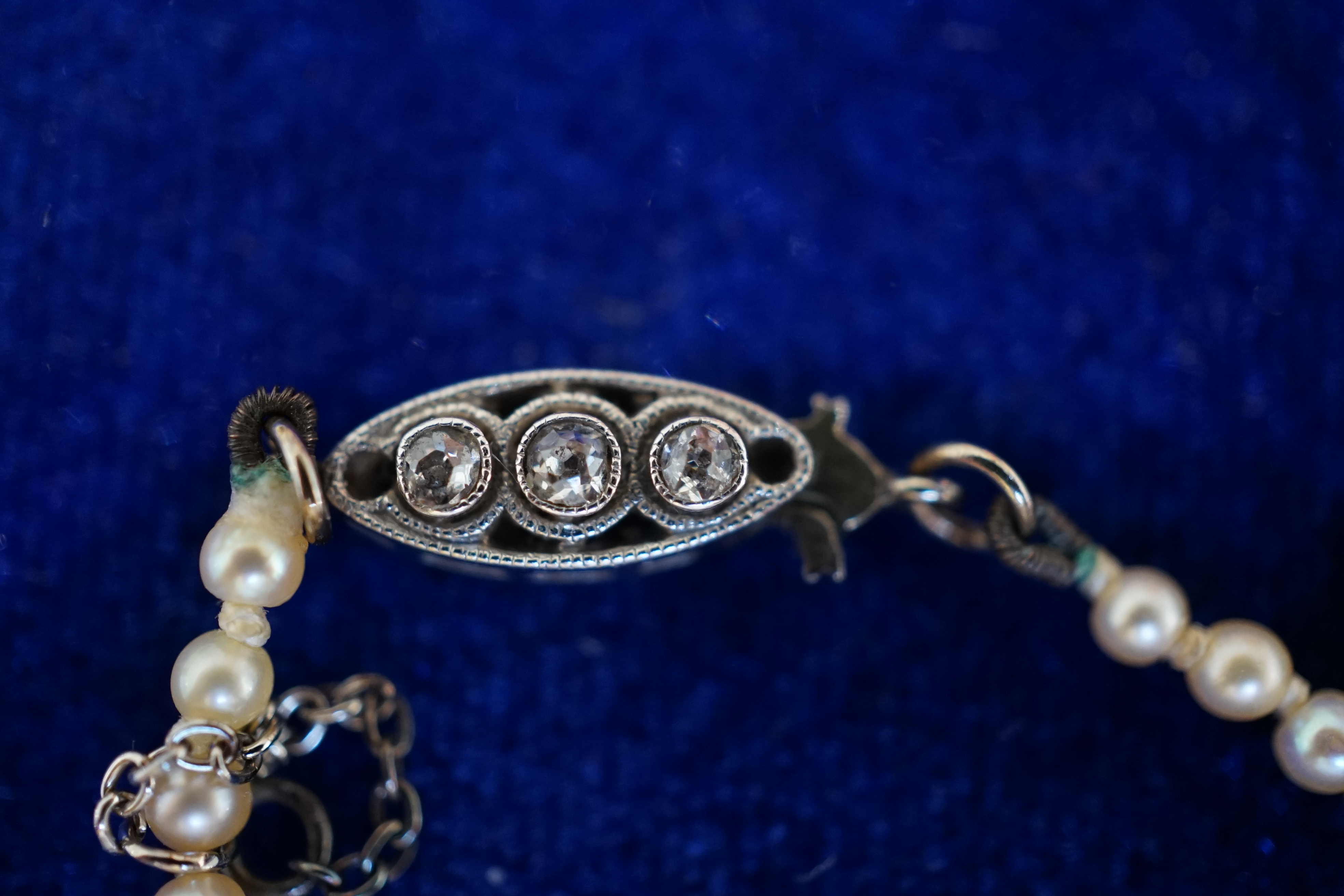 An early 20th century single strand graduated natural pearl and seed pearl necklace, with three stone diamond set clasp and Anchor Cert report dated 27/6/2014 stating an extensive sample to be natural pearls